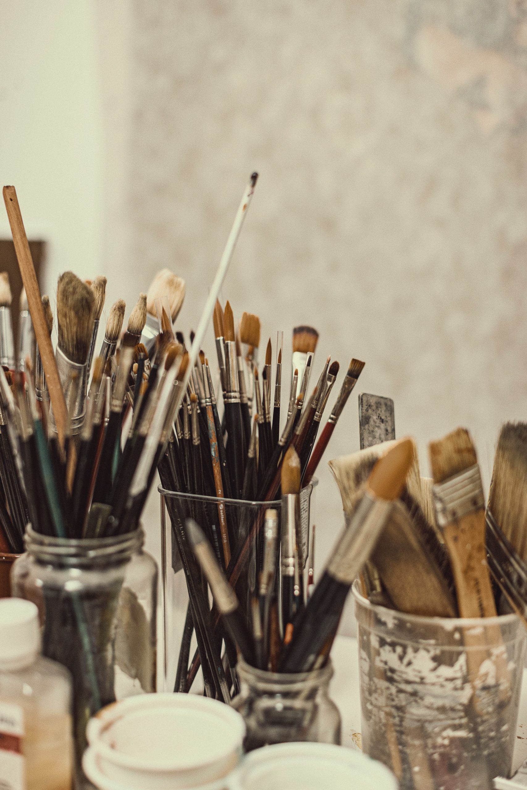 While you can buy paint brush holders, old jars and tins work just as well. Photo by Martin de Arriba on Unsplash
